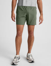 man wearing a gray t-shirt and green shorts on a white background.